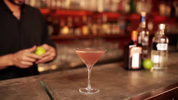 Bartender adding lime peel garnish to cosmopolitan