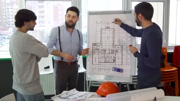 Architect Explaining Something on the Plan of the Building To His Colleagues