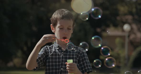 Slow motion of a boy blowing soap bubbles outdoors