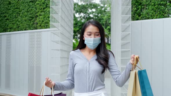 Asian woman wearing face mask. Happy woman with shopping bags