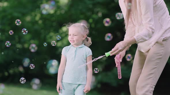 Family Having Fun. Mom And Child Making Soap Bubbles Outdoors