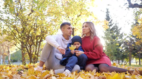 Mother Father and Son Spend Time Sitting on Yellow Leaves