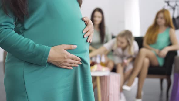Close-up of a Pregnant Woman in Blue-green Dress Caressing Her Belly. Expectant Woman with Her Three