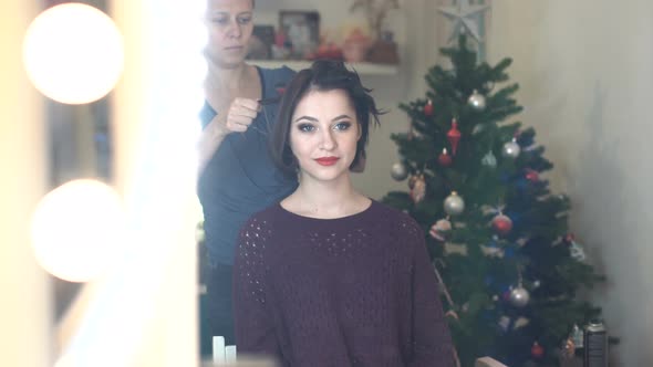 Woman Make-Up Artist Doing  Hair Styling To Beautiful Young Woman