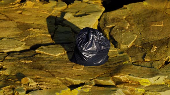 Black Trash Bag Lay on a Rocky Beach