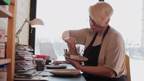 An Elderly Woman Covers a Clay Plate with a Special Solution