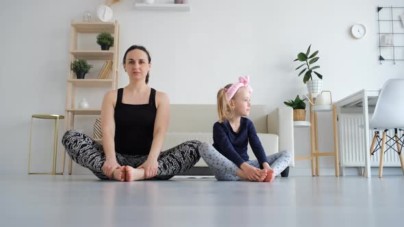 Young Woman with Little Daughter Practicing Yoga