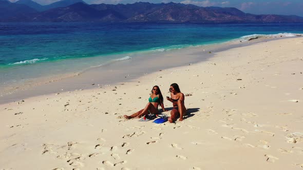 Sexy beauty models on holiday having fun at the beach on clean white sand and blue background 4K