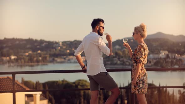 Romantic Couple Drinking Wine At Sunset. Couple Honeymoon Celebrating And Drinking Champagne.