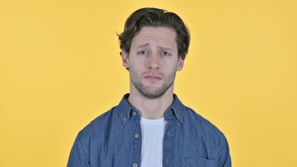 Serious Young Man Looking at the Camera on Yellow Background