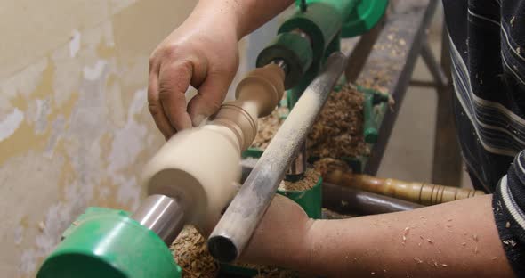 Closeup of person sanding wooden product using sandpaper on a lathe