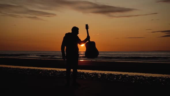 Man running with guitar in back sand beach at sunset. Beautiful, moody shots from the Sony a7iii.