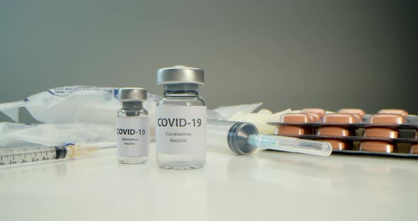 Vaccine Against COVID19 an Ampoule with a Vaccine Against Coronavirus and Various Syringes Nearby
