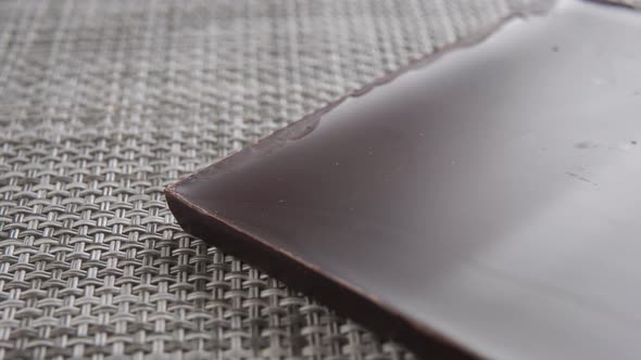 A slice of dark bitter chocolate close-up on a plastic mat