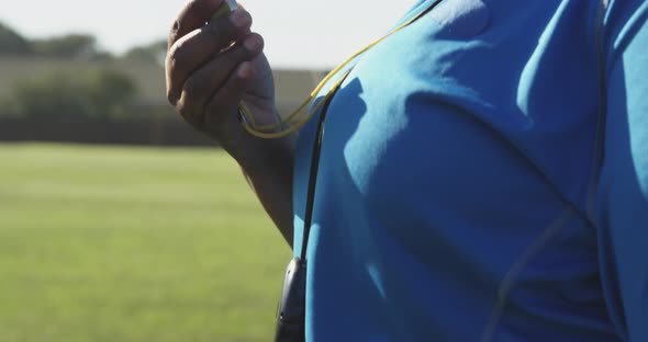 Female rugby coach blowing whistle