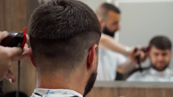 Barber Doing a Haircut to Male Client in Barbershop Close Up