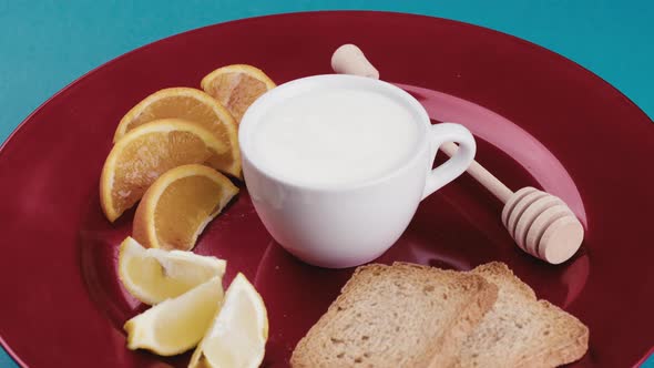 Cup of Fresh White Yogurt in a Red Plate with Fruit and Rusks for Breakfast