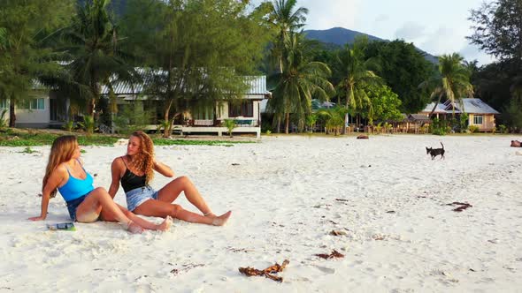 Beautiful ladies enjoying life on idyllic bay beach journey by blue lagoon and white sandy backgroun