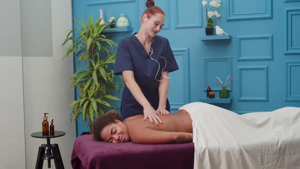 Cheerful Masseuse Working with Pleasure During Therapy Session Indoors