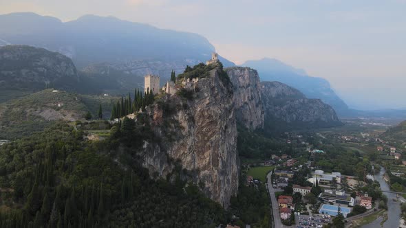 Ancient Arco castle on top of cliff above Riva Del Garda city, Trentino, Italy. Aerial view of fortr