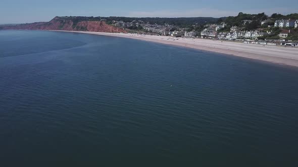 Wide aerial view of Budleigh Salterton, beach and rusty red cliffs from the sea side. Jurassic Coast