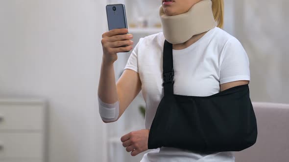 Sad Lady in Cervical Collar and Arm Sling Typing on Smartphone, Car Accident