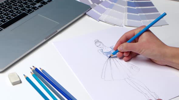 Designer with a Pencil Sketch Decorates Dresses in Blue. Close Up