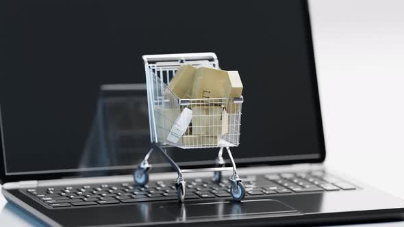 Concept of internet shopping. Cart full of packages placed on the open laptop.