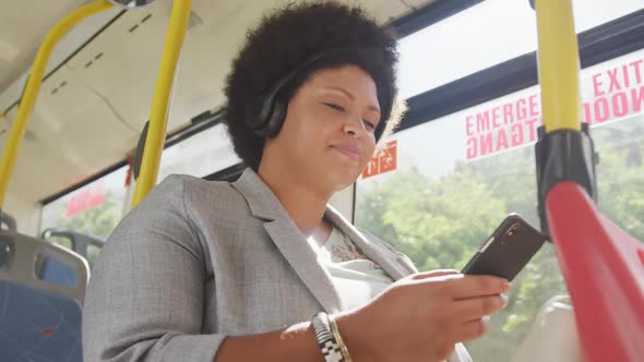 Happy plus size biracial woman using smartphone in bus