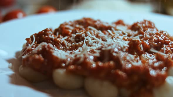Gnocci with Tomato Sauce Being Sprinkled with Parmesan