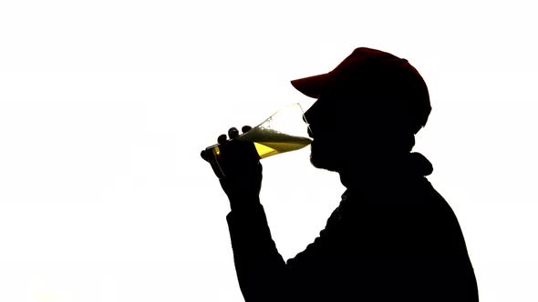 Bearded Man in a Cap Drinks Beer From a Glass, Side View, Silhouette White Background