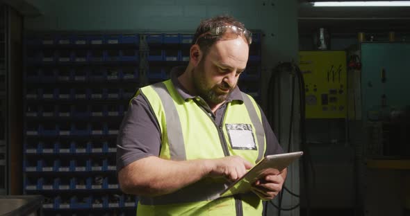 Caucasian male factory worker at a factory wearing a high vis vest working