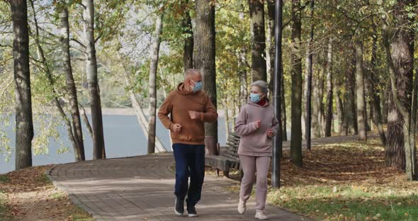 Wellness, Adult Couple Running Around a Forest Park, Autumn Day, Gray-haired Man and Woman Plays