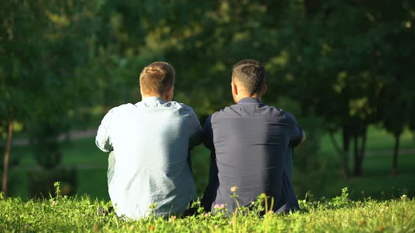 Back View of Men Talking and Relaxing at Sunny Park, Leisure Time With Friend