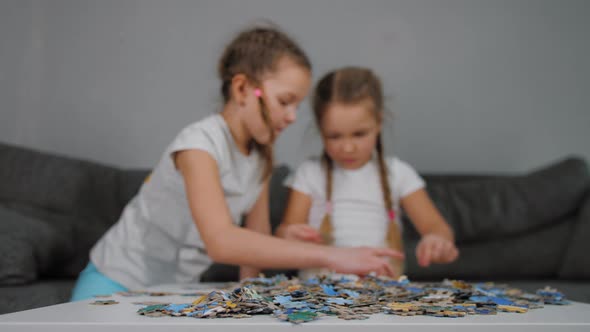 Two Little Sisters Pick Puzzle Detail Sitting on Sofa at Home