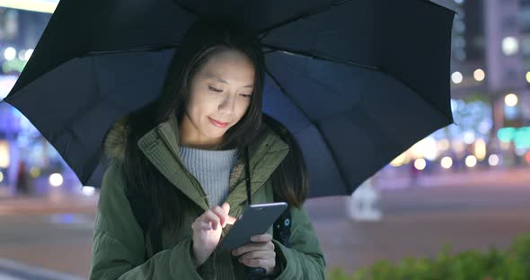 Woman use of smart phone and holding umbrella