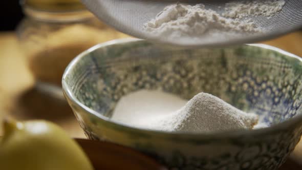 Woman Sifting Flour with a Sifter in the Kitchen with Sun Shining in Slow Motion Shot