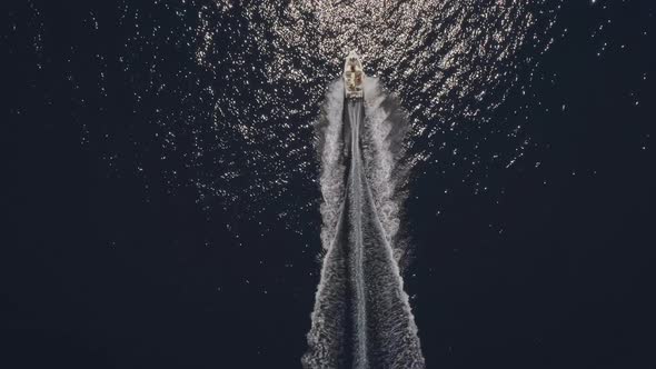 Aerial view of small speed boat with trailing wake on sea.