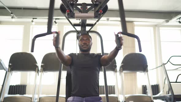 Muscular Man Do Exercises on Machine in Gym