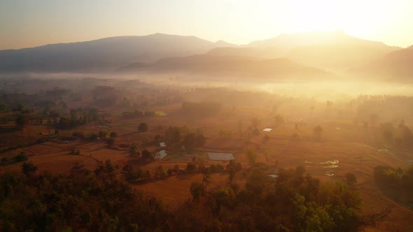 Aerial view over villages and barren fields in countryside during sunrise