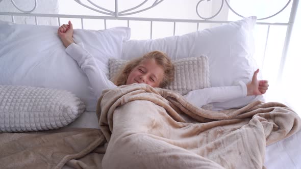 Two Little Children Wipe Their Eyes in Their Bed in the Morning Front View