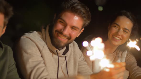 Happy Friends with Sparklers at Night Outdoors