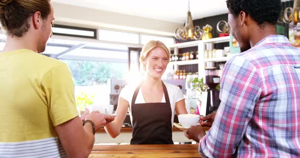 Smiling waitress serving cup of coffee to customer