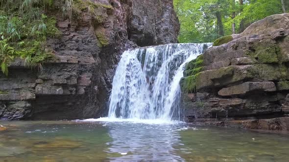 Waterfall on Mountain River with White Foamy Water Falling Down From Rocky Formation in Summer