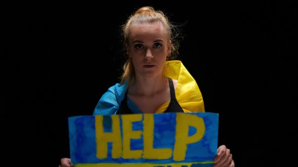 Desperate Woman Showing Help Ukraine Banner Looking at Camera with Hope