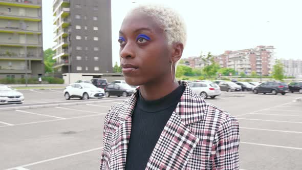 Young fashionable woman in checkered jacked standing on car park