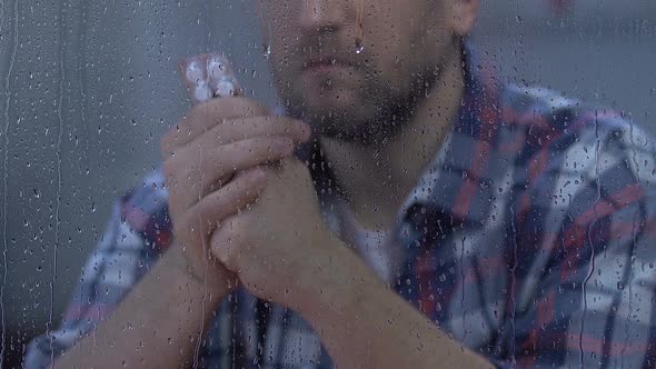 Male Holding Tablets and Looking to Rainy Window, Drug Side Effect, Disease