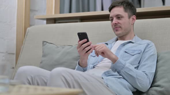 Relaxed Young Man Using Smartphone in Living Room