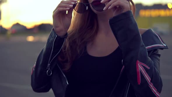 Young Charming Woman with Red Lips and Long Hair in Leather Jacket Wears Sunglasses