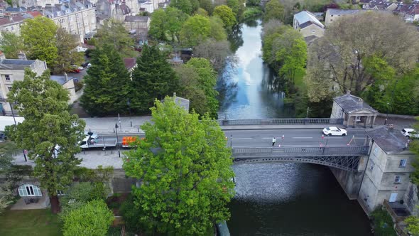 Aerial following traffic at speed as it filters across an old bridge in the English city of Bath